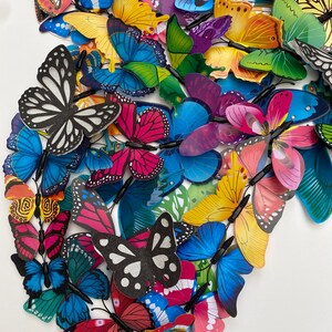 May include: A collection of colorful butterfly decorations with various patterns and designs. The butterflies are made of a lightweight material and have a wire attached to the back for easy hanging.