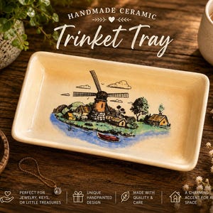 May include: A rectangular cream-colored ceramic trinket tray featuring a hand-painted illustration of a windmill, small houses, and a boat on a blue river. The text "HANDMADE CERAMIC Trinket Tray" is printed above the tray in a decorative font.