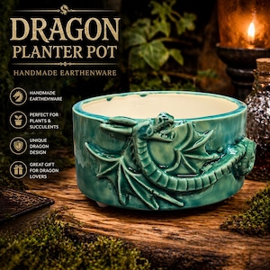 Puede incluir: Maceta de cerámica turquesa con un diseño detallado de dragón. La maceta es cilíndrica con un interior color crema y las palabras "DRAGON PLANTER POT" en la parte superior. Hecho a mano en cerámica.