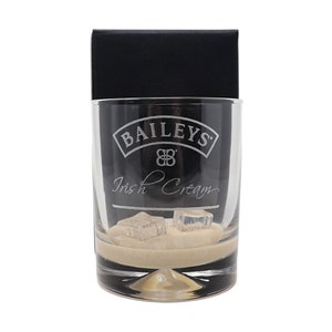 Peut inclure: Un verre en verre transparent avec le logo Bailey's Irish Cream gravé sur le côté. Le verre est rempli d'un liquide brun clair et de quelques glaçons.