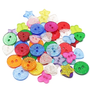 May include: Assortment of colourful, sparkly buttons in various shapes, including circles, stars, hearts, and flowers. The buttons are made of plastic and have a glittery finish.