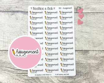 May include: A sheet of stickers with a pink background and a yellow pencil icon. The stickers feature the text "Assignment" with a squiggly underline. The sheet also includes three pink hearts.