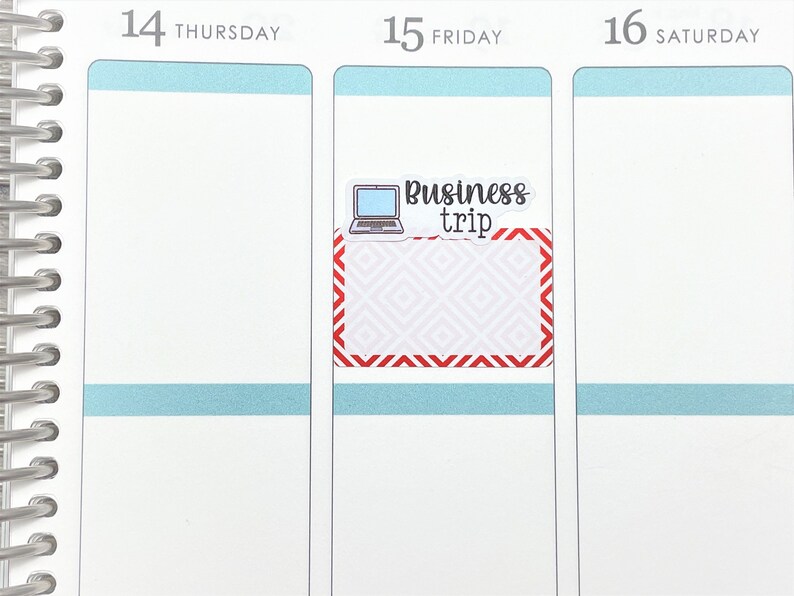 May include: A white planner with a red and white patterned sticker that says "Business trip" with a laptop icon. The planner has the days of the week labelled: Thursday, Friday, and Saturday.