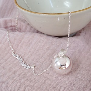 Peut inclure: Un collier en argent avec un pendentif rond en argent et une pierre rose à l'intérieur. Le pendentif est attaché à une délicate chaîne en argent avec un pendentif en forme de feuille.