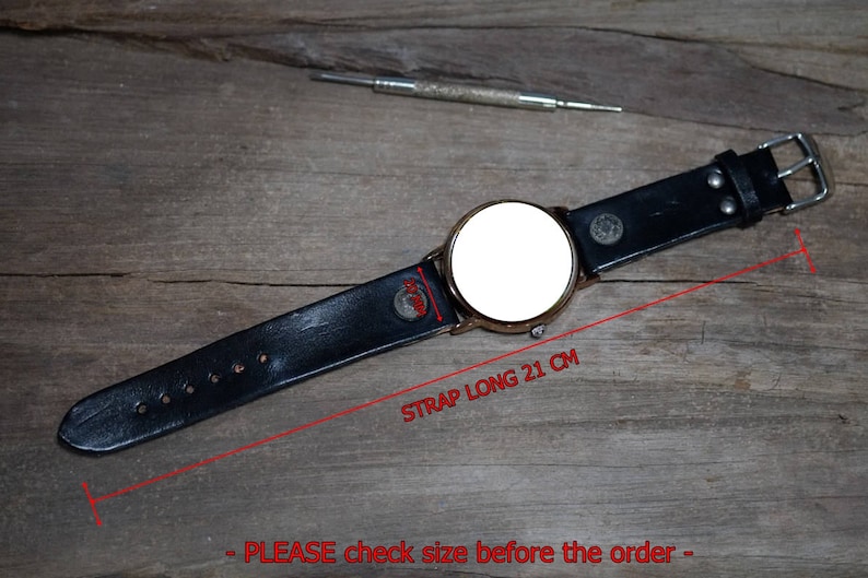 May include: A black leather watch strap with a gold-colored watch face. The strap is 21 cm long. A small tool is visible in the background. The watch has a silver buckle.