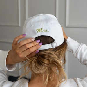 May include: White baseball cap with an embroidered green "Mrs." on the back.