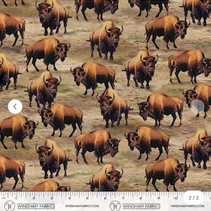 May include: Fabric with a repeating pattern of brown bison on a tan background. The bison have dark brown fur on their heads and shoulders, with lighter brown fur on their bodies. The fabric is from Windham Fabrics.