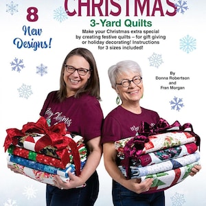 May include: A quilting pattern book titled Quick Christmas 3-Yard Quilts by Fabric Café, featuring 8 new designs. The cover displays text about creating festive quilts in 3 sizes, with illustrations of snowflakes and two stacks of folded quilts.