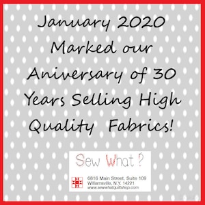 May include: A gray and white polka dot background with red border. The text "January 2020 Marked our Anniversary of 30 Years Selling High Quality Fabrics!" is in black. A white rectangle with a black border contains the text "Sew What?" in black. Below the text is a small red and white quilt block icon and the text "6816 Main Street, Suite 109 Williamsville, N.Y. 14221 www.sewwhatquiltshop.com" in black.