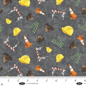 Op de afbeelding: Stof met een herhalend patroon van gele veiligheidshelmen, oranje verkeerskegels, groene ladders, rood-wit gestreepte bouwhekken en grijze rotsen op een donkergrijze achtergrond, met een liniaal in inches aan de onderkant.