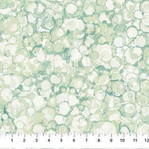 May include: A fabric featuring a pattern of overlapping circular shapes in various shades of sage green, mint, and white. A white ruler with black markings is visible at the bottom, showing measurements from 1 to 12 inches across the bottom edge.