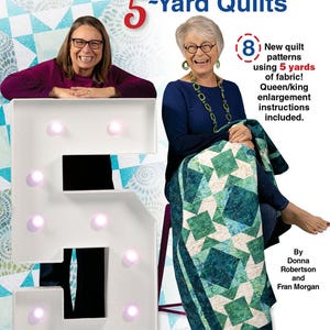 May include: Two women are sitting in front of a large white number 5. The woman on the left is wearing a purple shirt and the woman on the right is wearing a blue shirt. The woman on the right is holding a quilt with a green and white pattern. The text "Fabulous 5-Yard Quilts" is at the top of the image. The text "8 New quilt patterns using 5 yards of fabric! Queen/king enlargement instructions included." is on the right side of the image. The text "By Donna Robertson and Fran Morgan" is at the bottom right of the image.
