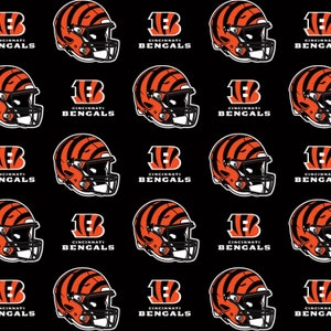 Può includere: Uno sfondo nero con un motivo ripetuto di caschi da football americano arancioni e neri e il logo dei Cincinnati Bengals. Il logo è una 'B' bianca con il numero '1' all'interno e le parole 'Cincinnati Bengals' sotto.