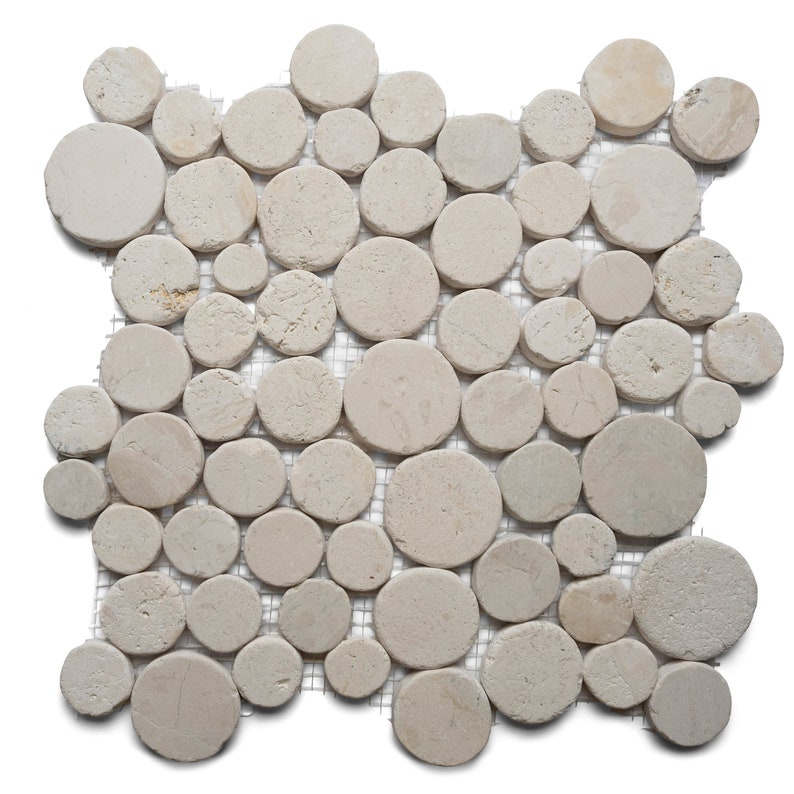 May include: A mosaic tile sheet featuring numerous beige, circular stones of varying sizes. The stones are arranged closely together and mounted on a mesh backing. The natural stone has a slightly rough texture and a neutral color palette.