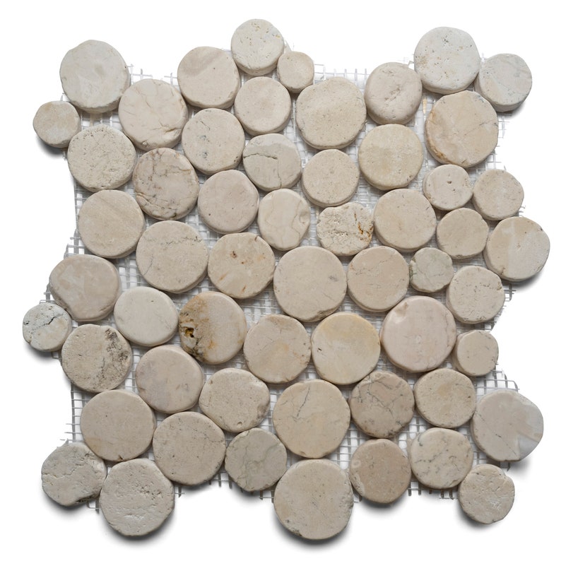 May include: A mosaic tile sheet composed of numerous beige, circular stones. The stones vary slightly in color and size, arranged on a mesh backing. Ideal for flooring or wall decor, the natural stone tiles offer a rustic aesthetic.