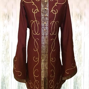 May include: A maroon long-sleeved shirt with gold embroidery and a high collar. The shirt has a button-up front and a decorative trim around the edges.