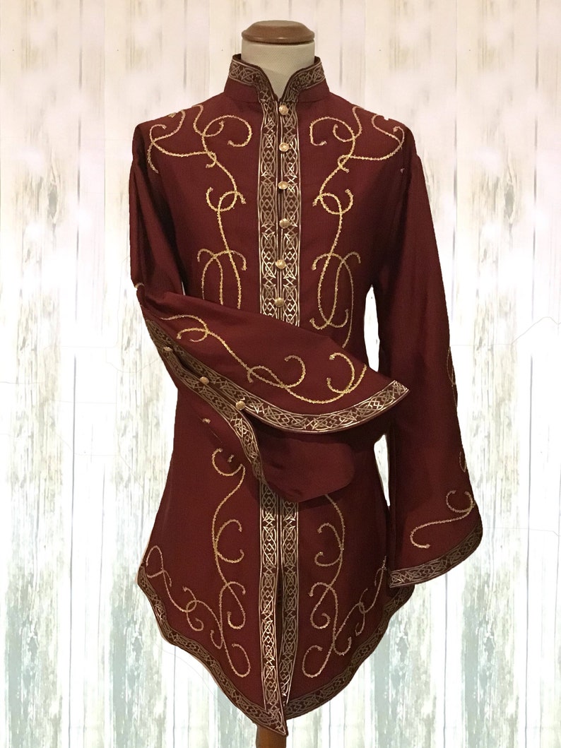 May include: A burgundy long-sleeved shirt with gold embroidery and trim. The shirt has a high collar and a button-up front.