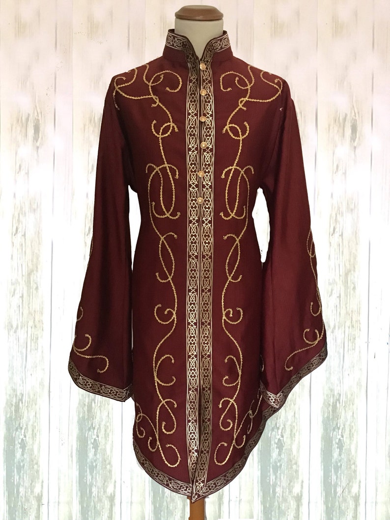 May include: A long-sleeved burgundy shirt with a high collar and gold embroidery. The embroidery features a repeating pattern of swirls and lines.