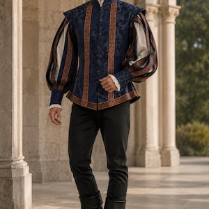 Puede incluir: Un jubón azul oscuro con un sutil estampado floral, que presenta mangas largas abullonadas con mangas interiores blancas, cuello alto y ribetes naranjas. La prenda se combina con pantalones negros y botas de cuero negro con vuelta.