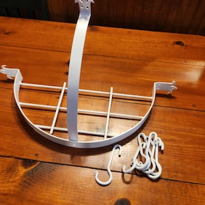 May include: White metal hanging basket with a curved design and grid interior. Includes a long, vertical support and several S-hooks. The basket is designed to hang from a ceiling or wall, perfect for displaying plants or other items.