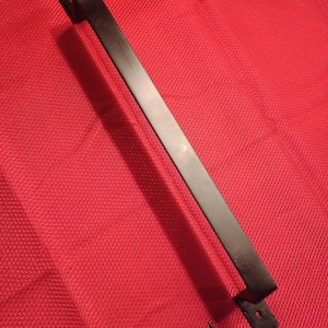 May include: A black metal door pull with a rectangular bar and curved handles. The door pull is approximately 12 inches long and includes a screw for installation. The background is a red fabric.
