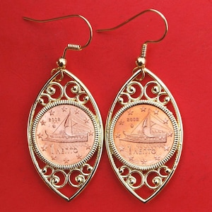 May include: A pair of gold earrings featuring a 2002 Greek 1 Lepton coin with a ship design. The coins are set in an oval-shaped filigree frame.