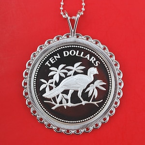 May include: Silver pendant necklace featuring a silver coin with a bird and palm trees design. The coin has the text "TEN DOLLARS" around the edge.