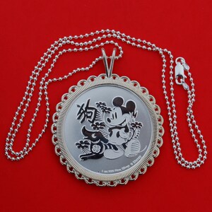 May include: A silver necklace with a round pendant featuring a black and white image of Mickey Mouse and the Chinese character for "Year of the Rat". The pendant is inscribed with "1 oz .999 Fine Silver &copy; Disney".