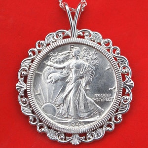 May include: Silver pendant necklace featuring a 1943 Walking Liberty Half Dollar coin with an ornate silver frame. The coin depicts Lady Liberty walking forward with a torch and an olive branch.