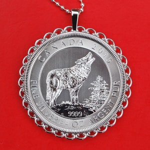 May include: Silver Canadian Wolf coin pendant featuring a detailed image of a wolf howling at the moon. The coin is dated 2015 and has "Fine Silver 9999" inscribed around the edge.