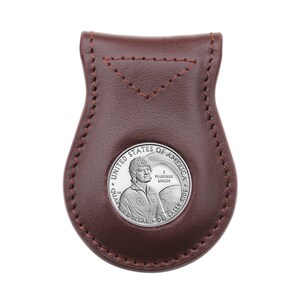 Puede incluir: Una cartera de monedas de cuero marrón con una moneda de plata que presenta un retrato de Sally Ride, la primera mujer estadounidense en el espacio. La moneda dice "United States of America, E Pluribus Unum, Quarter Dollar, Dr. Sally Ride".