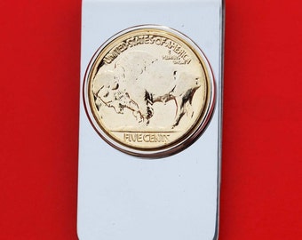 May include: A silver money clip with a gold-toned buffalo nickel coin design. The coin features the words "United States of America" and "Five Cents" along with an image of a buffalo.