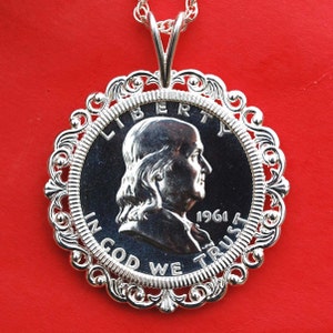 Può includere: Collana con ciondolo in argento con una moneta da mezzo dollaro del 1961 con un profilo di Benjamin Franklin. La moneta è circondata da una cornice in argento decorata con un motivo a volute.