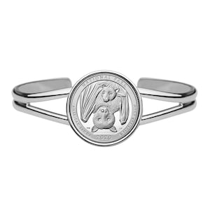 May include: A silver bracelet featuring a 2020 American Samoa National Park quarter with a bat design. The coin displays the words "National Park" and "American Samoa".