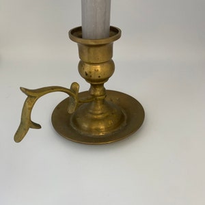 Peut inclure: Un chandelier en laiton avec une poignée et une base ronde. Le chandelier est conçu pour tenir une seule bougie.
