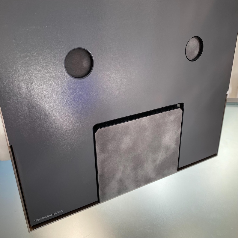 May include: A black speaker with two round speaker grilles and a rectangular opening on the bottom. The speaker has a label on the bottom that reads 'PS-NCF-LW01135/1407'. 