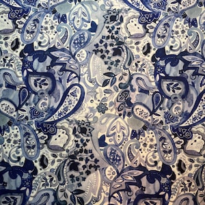 Pode incluir: Um padrão de aquarela repetitivo com formas de paisley e elementos florais em tons de azul e branco. O design tem um toque suave e artístico, com variações na intensidade da cor que criam profundidade.