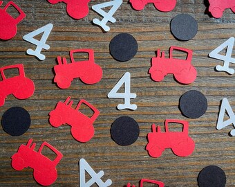 May include: Red and white paper cutouts of tractors and the number four. There are also black circles scattered throughout the image.