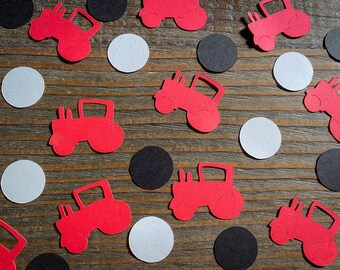 May include: Red and black paper confetti featuring a tractor design. The confetti is scattered on a wooden surface.