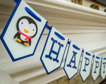 Pode incluir: Uma faixa azul e branca com a palavra "HAPPY" escrita em letras azuis. A faixa tem um pinguim com uma echarpe vermelha na primeira bandeira.