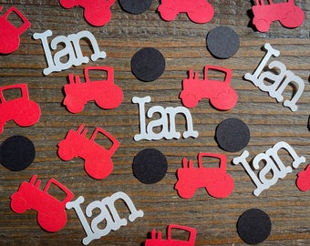 May include: Red and white paper cutouts of tractors and the name Ian. The cutouts are scattered on a wooden surface.