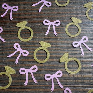 Lazo rosa Ella está atando el nudo Confeti con anillos dorados