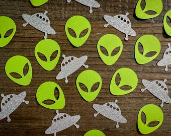 Könnte beinhalten: Grüner und silberner Alien- und Raumschiff-Konfetti. Der Konfetti ist aus Papier ausgeschnitten und hat eine Glitzer-Oberfläche.