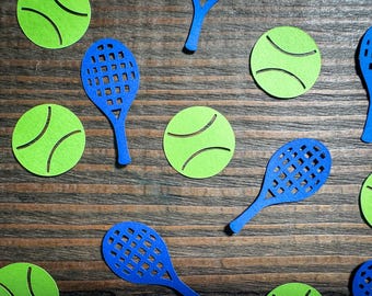 May include: A collection of blue paper tennis rackets and green paper tennis balls on a brown wooden surface.
