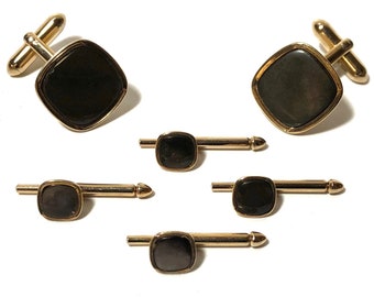 May include: A set of five gold-toned cufflinks and collar stays. The cufflinks and collar stays feature black square-shaped stones.