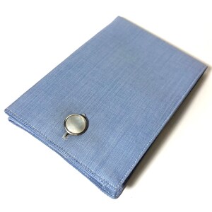 Puede incluir: Una caja de gemelos azul claro con un gemelo de n&aacute;car blanco en su interior.