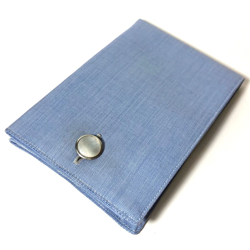 Puede incluir: Una caja de gemelos azul claro con un gemelo de n&aacute;car blanco en su interior.