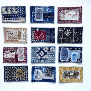 May include: A collection of twelve rectangular fabric patches featuring various textile designs, including indigo blue, red, and mustard yellow patterns, with visible hand-stitched embroidery, frayed edges, and vintage-style printed ephemera.