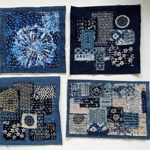 May include: Four indigo-dyed fabric squares with visible stitching. Each square features a unique design, including tie-dye patterns, floral motifs, and geometric shapes. The squares are arranged on a white surface, showcasing the intricate details of the textile art.