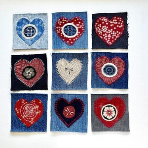 May include: Nine denim fabric squares, each featuring a heart design. The hearts are appliqued with various patterns and colors, including red, white, and blue floral and geometric motifs. The squares are arranged in a grid pattern.